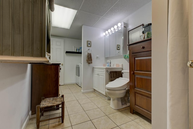 bathroom with vanity, washer / dryer, toilet, a paneled ceiling, and tile patterned floors