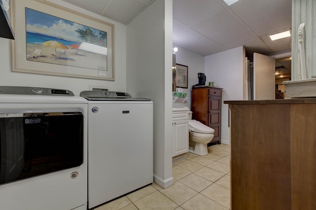 laundry area featuring baseboards, washing machine and dryer, and light tile patterned flooring