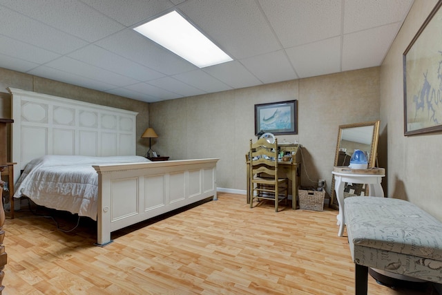 bedroom with light wood-style floors and a paneled ceiling