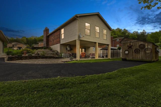 back of house featuring a lawn and a chimney