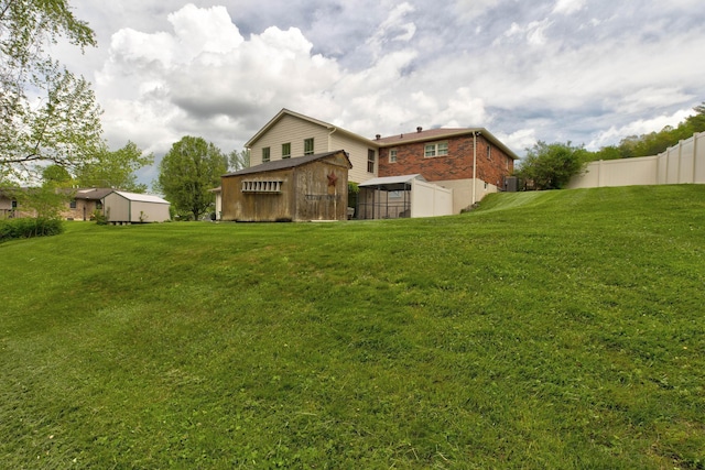rear view of house featuring an outbuilding, fence, and a yard