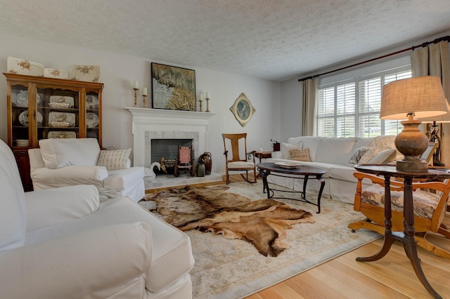 living area featuring a textured ceiling, wood finished floors, and a fireplace