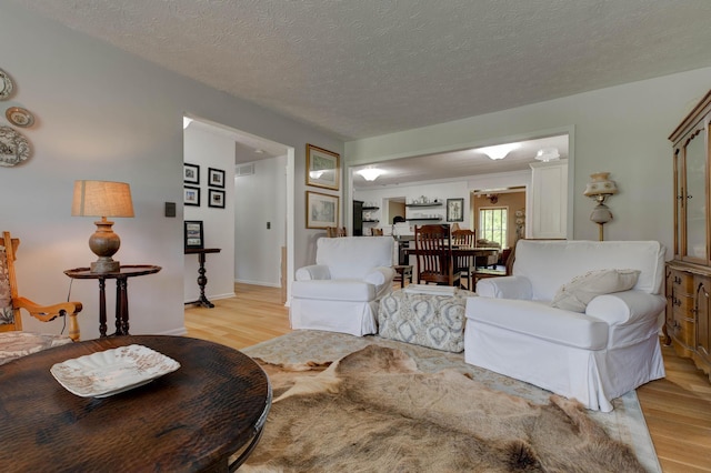 living room with light wood-style floors, a textured ceiling, and visible vents