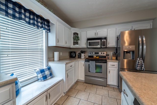 605 Coleman Dr, Berea, KY 40403 - kitchen with light tile patterned flooring, white cabinetry, light countertops, glass insert cabinets, and appliances with stainless steel finishes