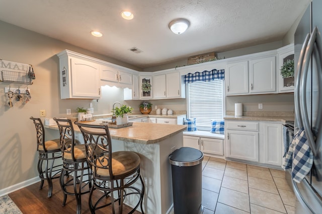 605 Coleman Dr, Berea, KY 40403 - kitchen featuring white cabinetry, light countertops, a kitchen breakfast bar, and glass insert cabinets