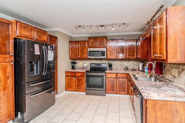 kitchen featuring appliances with stainless steel finishes, a sink, decorative backsplash, light tile patterned floors, and ornamental molding