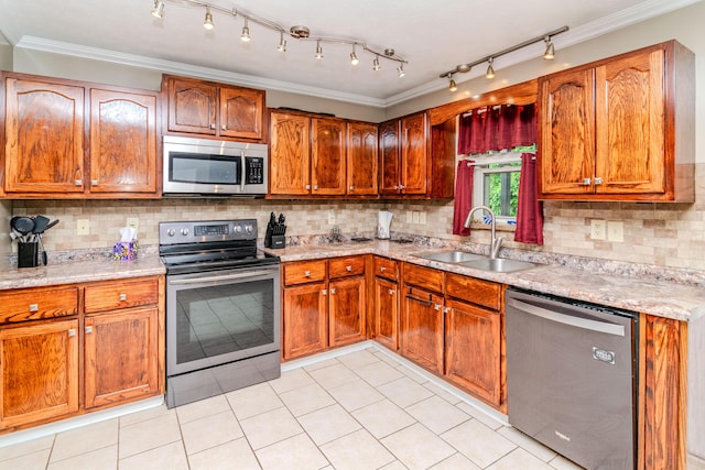 kitchen with crown molding, appliances with stainless steel finishes, a sink, light tile patterned floors, and backsplash