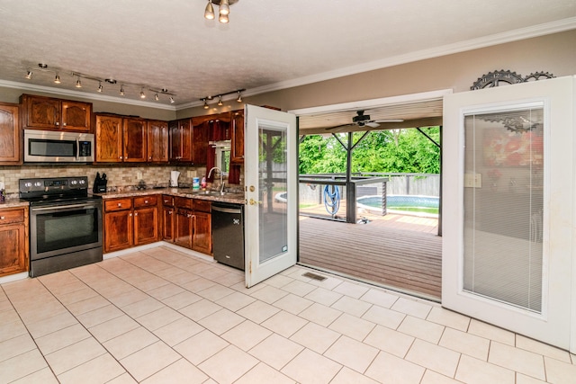 kitchen featuring track lighting, ornamental molding, light stone countertops, and stainless steel appliances