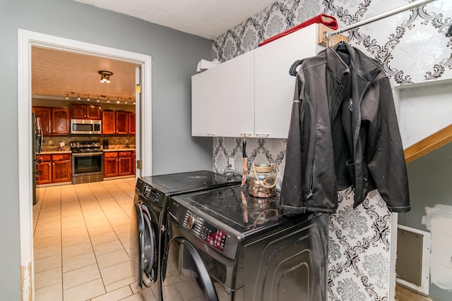 laundry area featuring cabinet space, light tile patterned floors, and washer and clothes dryer