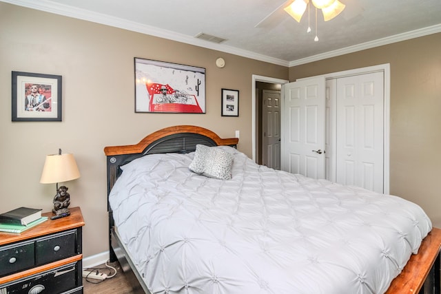 bedroom with baseboards, wood finished floors, visible vents, ornamental molding, and a closet