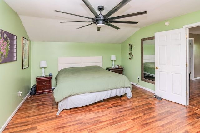 bedroom featuring baseboards, wood finished floors, and vaulted ceiling