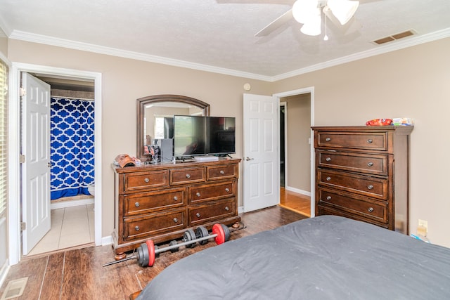 bedroom with crown molding, visible vents, and wood finished floors