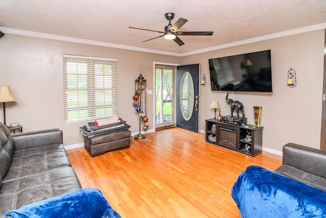 living room with baseboards, a ceiling fan, crown molding, and wood finished floors