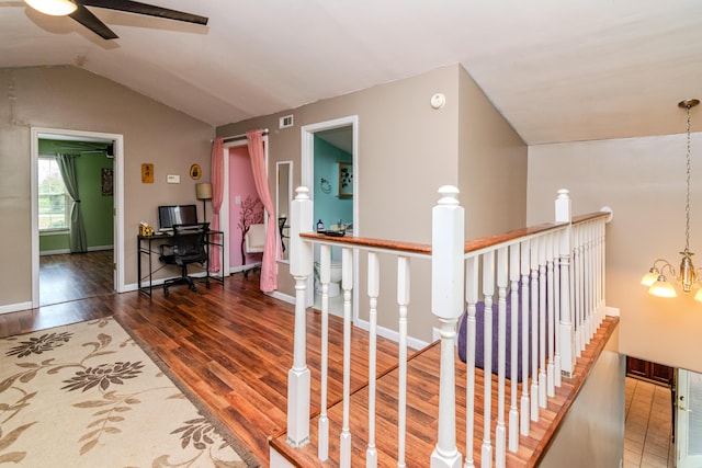 corridor with an inviting chandelier, an upstairs landing, wood finished floors, lofted ceiling, and visible vents