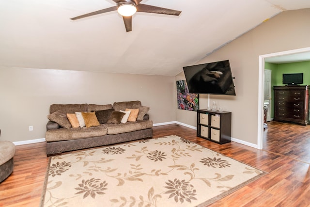 living room featuring baseboards, ceiling fan, vaulted ceiling, and wood finished floors