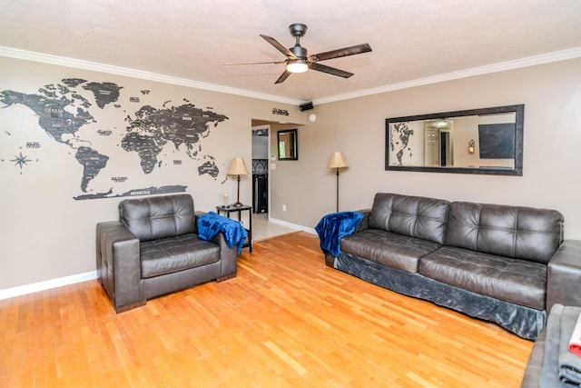 living room featuring baseboards, ceiling fan, crown molding, and wood finished floors