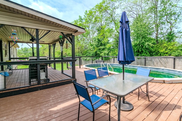 wooden terrace with a fenced in pool, a fenced backyard, ceiling fan, and outdoor dining space