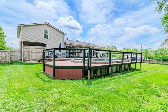 rear view of house featuring a lawn, a wooden deck, a gate, a fenced backyard, and a jacuzzi