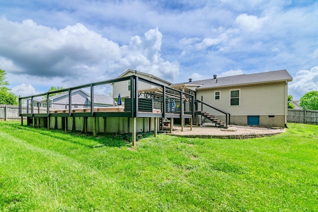 rear view of house featuring a lawn, fence, a wooden deck, and stairs