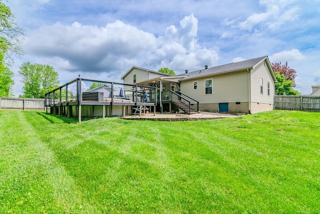 rear view of house with a fenced backyard, a deck, a lawn, and stairway