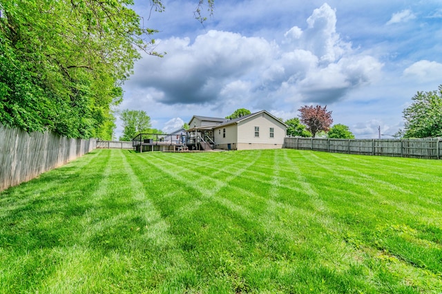 view of yard with a fenced backyard, a deck, and stairway