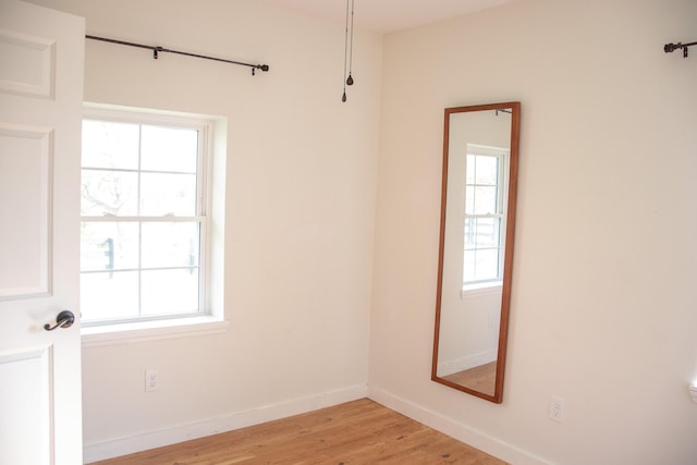 spare room with baseboards and light wood-style flooring