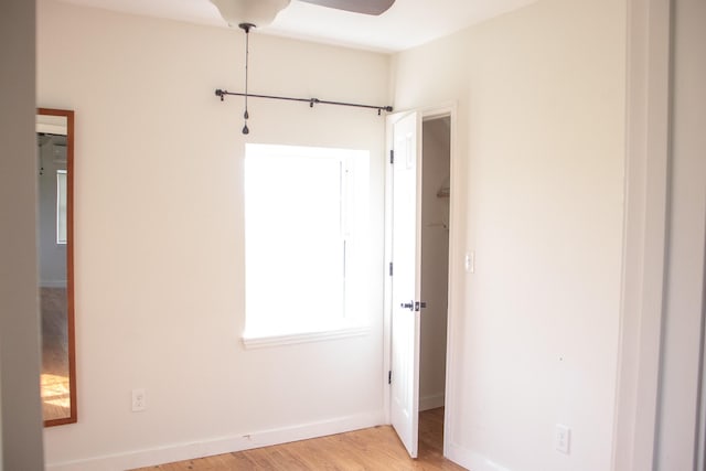 empty room with baseboards, ceiling fan, and light wood finished floors