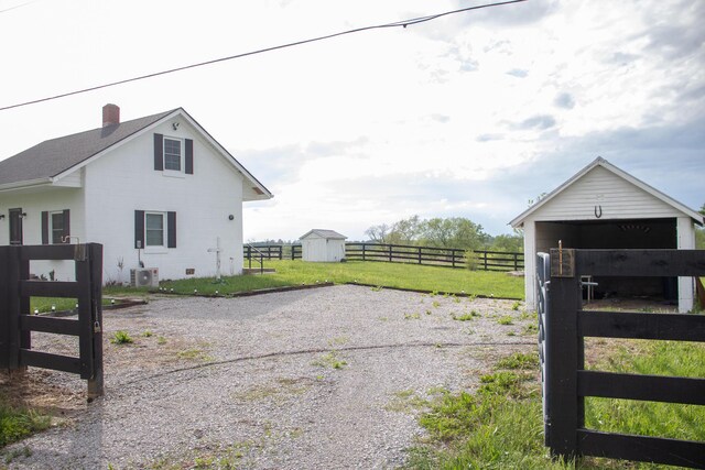 view of gate with fence, an outdoor structure, and a shed
