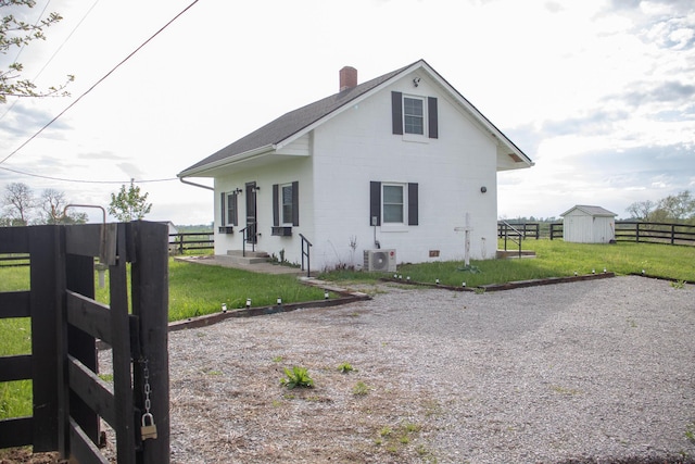 back of property featuring a yard, fence, a chimney, and an outbuilding