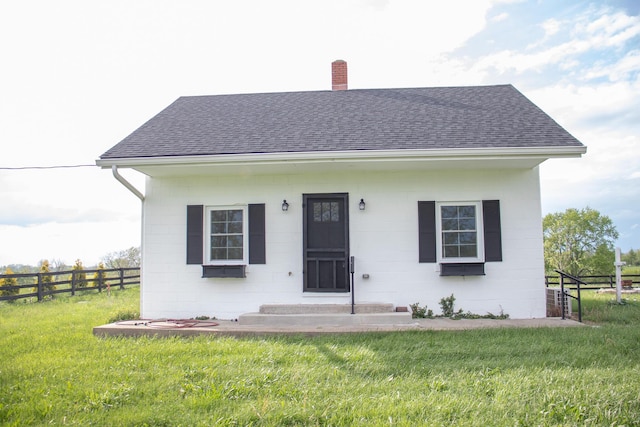 view of front of home with roof with shingles, fence, a chimney, and a front lawn