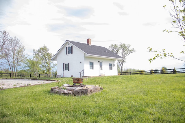 back of house featuring a fire pit, fence, a yard, and a chimney