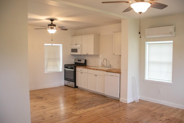 kitchen featuring a sink, a ceiling fan, a wall mounted air conditioner, and white appliances
