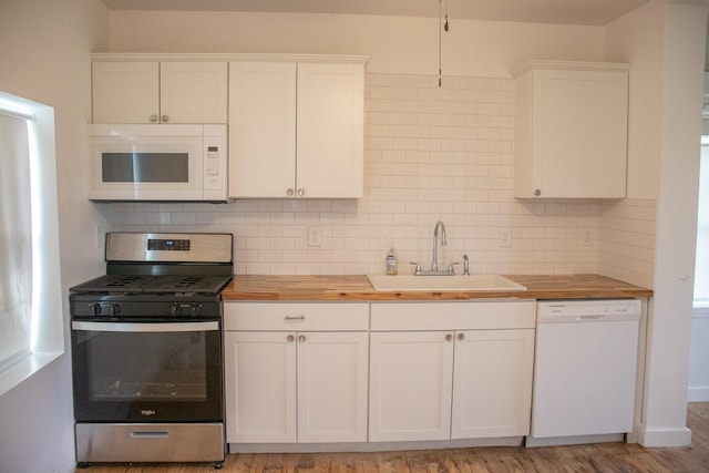 kitchen with butcher block counters, white appliances, white cabinets, a sink, and backsplash