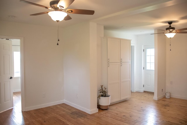 unfurnished room with baseboards, ceiling fan, and light wood-type flooring