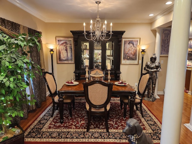 dining area featuring ornate columns, wood finished floors, a chandelier, crown molding, and baseboards