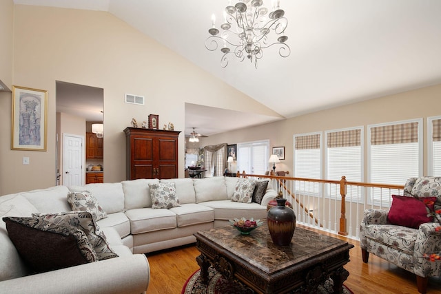 living area with light wood finished floors, a chandelier, high vaulted ceiling, and ceiling fan
