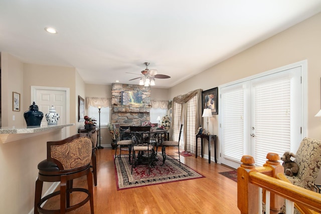 dining room featuring ceiling fan, light wood finished floors, recessed lighting, a fireplace, and baseboards