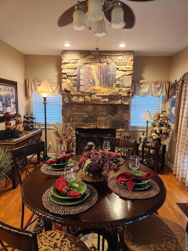 dining space with wood finished floors, healthy amount of natural light, a stone fireplace, and baseboards