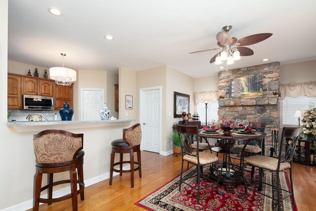 dining room with ceiling fan, light wood finished floors, baseboards, and recessed lighting