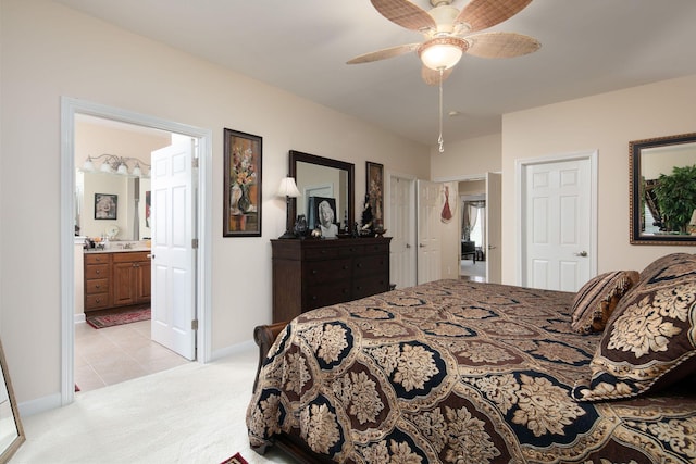 bedroom featuring light carpet, baseboards, light tile patterned floors, ensuite bath, and a ceiling fan