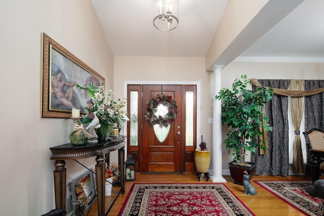 foyer featuring decorative columns and wood finished floors