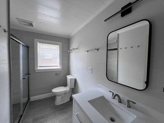 422 Wilderness Rd, Middlesboro, KY 40965 - bathroom featuring a stall shower, toilet, vanity, crown molding, and tile walls