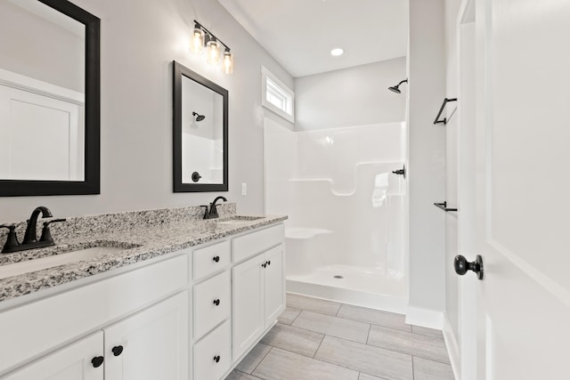 full bath with double vanity, walk in shower, and a sink