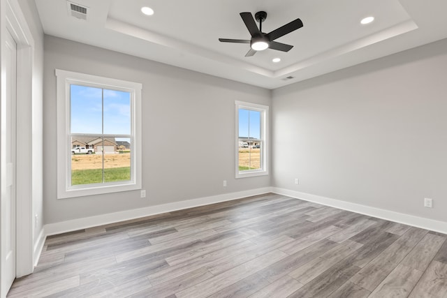 unfurnished room featuring a ceiling fan, visible vents, a raised ceiling, light wood-style floors, and recessed lighting