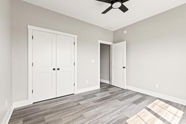 unfurnished bedroom with a closet, baseboards, ceiling fan, and light wood-style floors