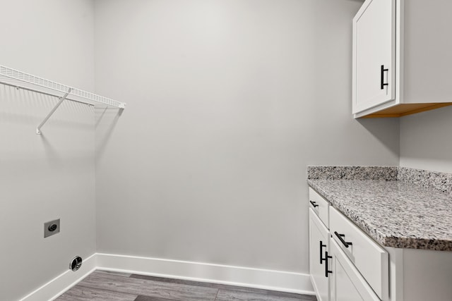 laundry area with baseboards, hookup for an electric dryer, and wood finished floors