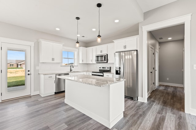 kitchen with backsplash, white cabinets, appliances with stainless steel finishes, and wood finished floors