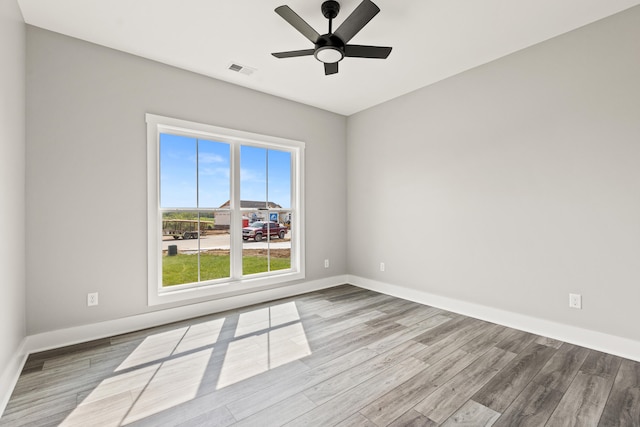 unfurnished room with baseboards, a ceiling fan, wood finished floors, and visible vents