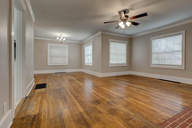 empty room with a chandelier, wood finished floors, ceiling fan, crown molding, and baseboards