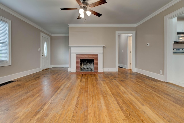 unfurnished living room featuring a ceiling fan, light wood-style floors, a brick fireplace, ornamental molding, and baseboards